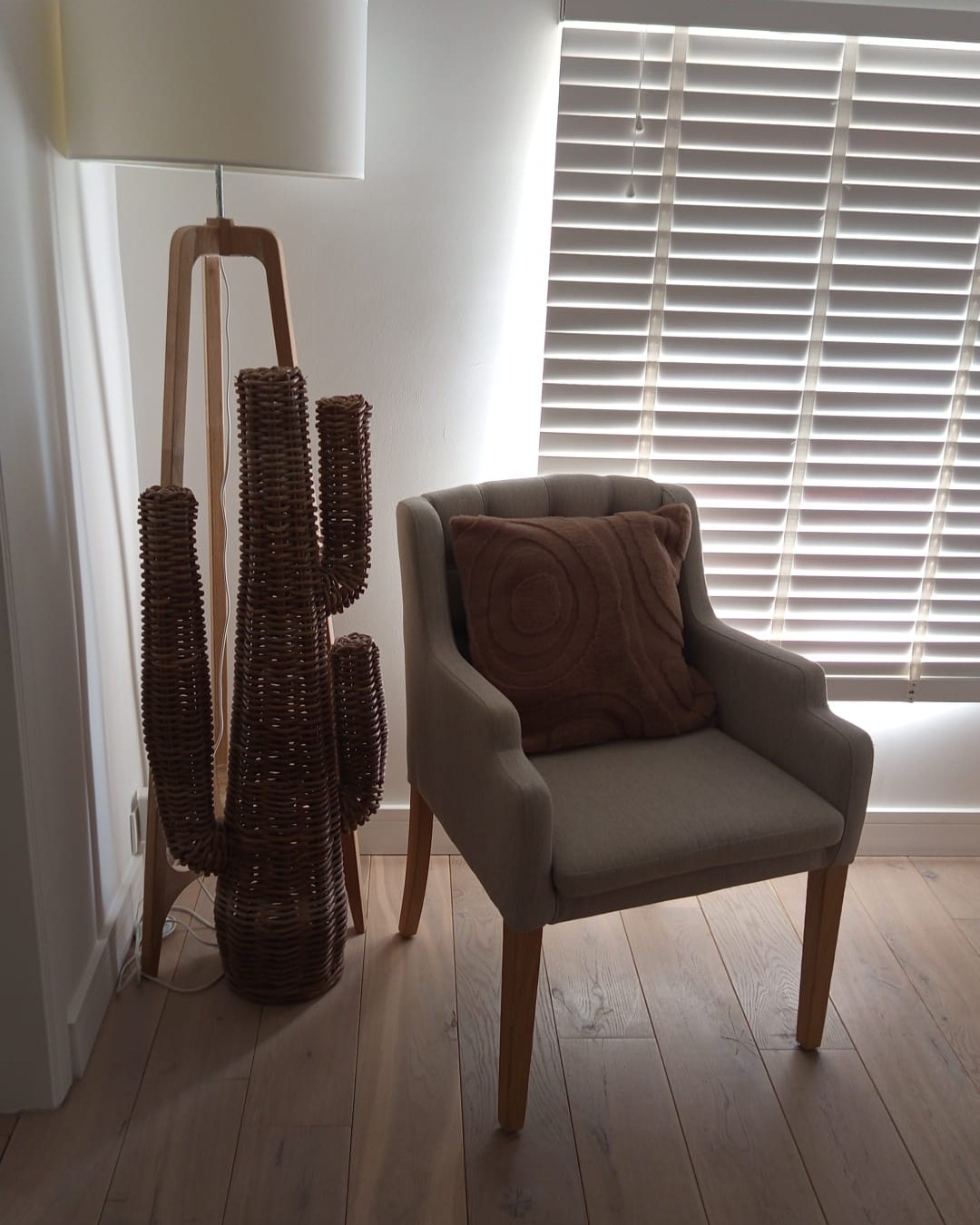 Le coin salon : le lampadaire, le cactus en rotin et le fauteuil dans la lumière du jour